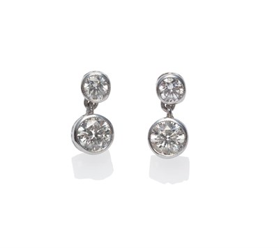 Lot 282 - A Pair of Diamond Two Stone Earrings, each comprises a round brilliant cut diamond stud, suspending