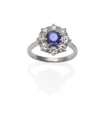 Lot 294 - A Sapphire and Diamond Cluster Ring, the round mixed cut sapphire within a border of eight...