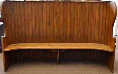 Lot 970 - A Pine Country Settle, 19th century, of bowed form, with planked panelled back between shaped wings