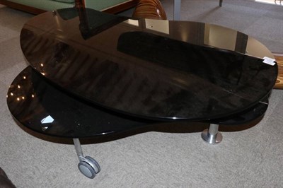 Lot 3015 - A Black Glass Coffee Table, modern, of kidney shape form raised on polished tubular legs with large