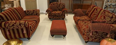 Lot 3195 - A Three Piece Suite and Footstool, modern, comprising a Buckingham three-seater sofa covered in red