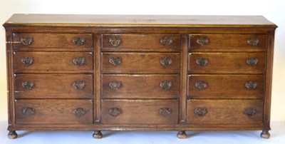 Lot 3008 - A Reproduction Oak Dresser Base, with twelve graduated drawers with solid backplate drop...