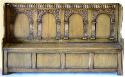 Lot 3023 - A Reproduction Oak Wing-Back Pew, with fluted top rail above four arched panels, the hinged...