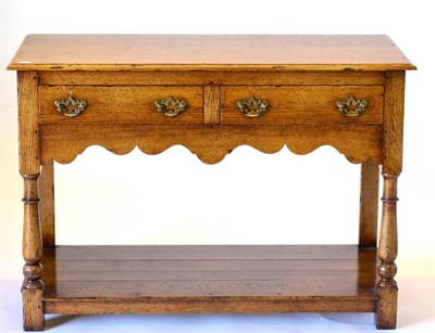 Lot 3030 - A Reproduction Oak Two Drawer Hall Table, with two frieze drawers above a wavy shaped apron, raised