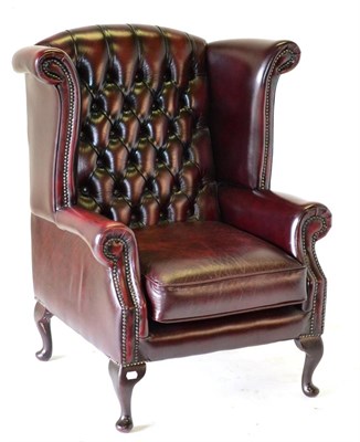 Lot 3207 - A Wing-Back Armchair, labelled Thomas Lloyd, upholstered in buttoned and close-nailed ox blood...