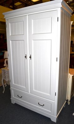 Lot 1034 - A White Painted Double Door Wardrobe of recent date, panel doors enclosing a hanging rail and shelf