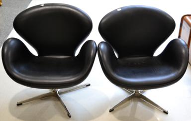 Lot 1144 - A Pair of Arne Jacobsen Style Swan Chairs of recent date, upholstered in black leather, raised...