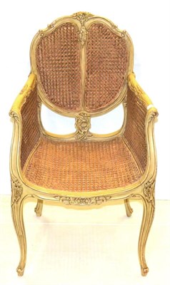 Lot 1172 - A Cream Painted Double Caned Bergere in the Louis XV style, with carved and moulded frame raised on