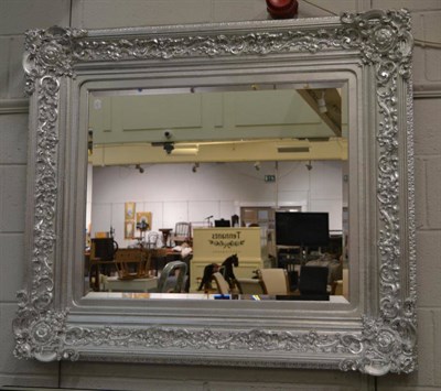 Lot 1116 - A Reproduction Silver Painted Bevelled Glass Mirror, of recent date, the scrolled frame with an egg