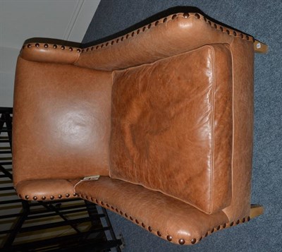 Lot 1146 - An Easy Chair, of recent date, upholstered in light brown close-nailed leather, the squab...