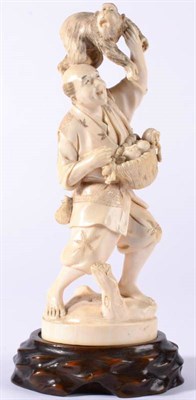 Lot 92 - A Japanese Ivory Okimono, Meiji period, as a farmer carrying a basket of fruit, a monkey on his...