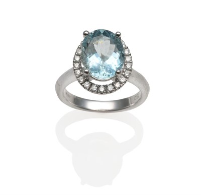 Lot 187 - An 18 Carat White Gold Aquamarine and Diamond Cluster Ring, the oval cut aquamarine over a...