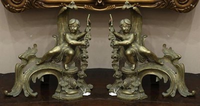 Lot 281 - A Pair of 19th Century Brass Chenets, in the rococo style, each modelled as a putto holding a...