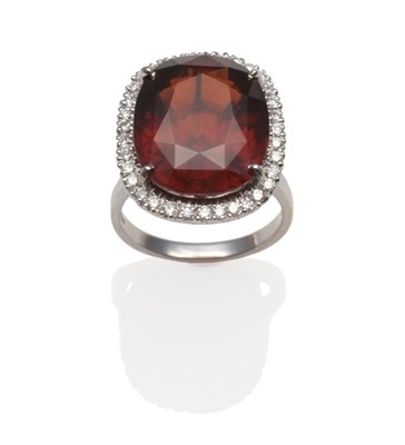 Lot 236 - An 18 Carat White Gold Garnet and Diamond Cluster Ring, the oval mixed cut garnet within a...