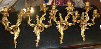 Lot 362 - A Set of Four Gilt Bronze Three-Light Wall Lights, in Louis XV style, with fluted sconces and...