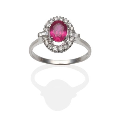 Lot 263 - An 18 Carat White Gold Ruby and Diamond Cluster Ring, the oval mixed cut ruby within a border...