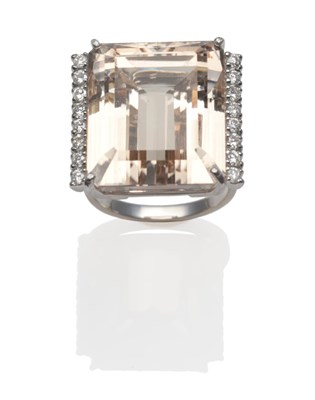 Lot 312 - An 18 Carat White Gold Topaz and Diamond Ring, the emerald-cut peachy coloured topaz with a row...