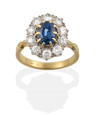 Lot 679 - A Sapphire and Diamond Cluster Ring, an oval cut sapphire in a claw setting, within a border of...