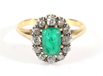 Lot 680 - An Emerald and Diamond Cluster Ring, an octagonal cut emerald in a claw setting, within a border of