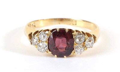 Lot 696 - A Ruby and Diamond Ring, an oval cut ruby spaced by groups of three old cut diamonds, total...