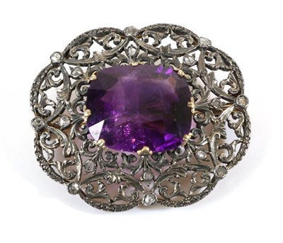 Lot 716 - An Amethyst and Diamond Brooch, a cushion cut amethyst in a claw setting, to a pierced scroll frame