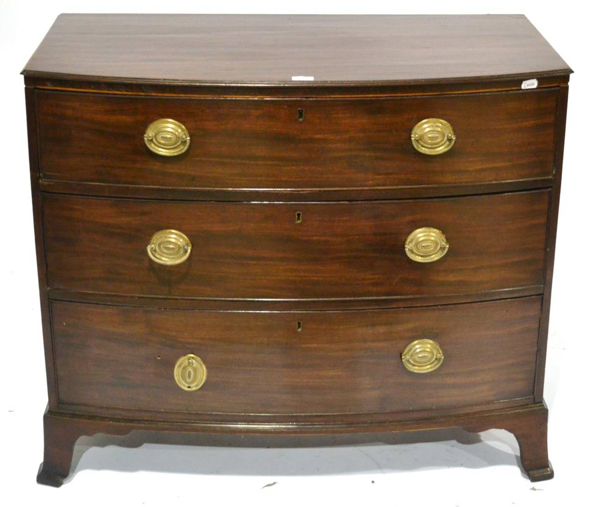 Lot 343 - A George III Mahogany Bowfront Chest, circa 1800, the three deep graduated drawers with brass...