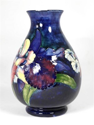 Lot 142 - Moorcroft Pottery: Walter Moorcroft Orchid and Spring Flowers pattern vase, on a blue ground,...