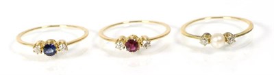 Lot 254 - A set of three rings, comprising; a ruby and diamond three stone ring, a pearl and diamond...