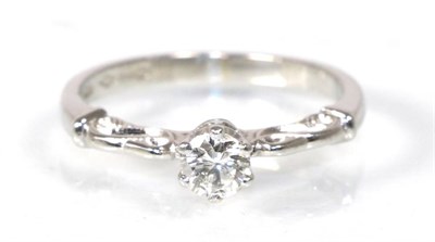 Lot 290 - A platinum solitaire diamond ring, a round brilliant cut diamond in a claw setting, to fancy scroll