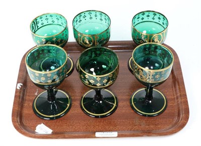 Lot 439 - A set of six gilt highlighted Victorian green glass wines decorated with an armorial