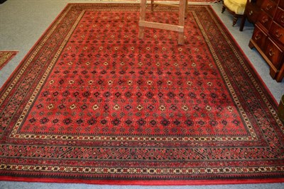 Lot 1307 - A machine made carpet of Turkmen design, the crimson field with columns of guls enclosed by stepped