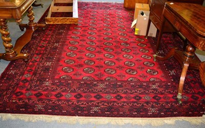 Lot 1317 - A machine made carpet of Chi Chi design, the brick red field of hooked guls enclosed by indigo...