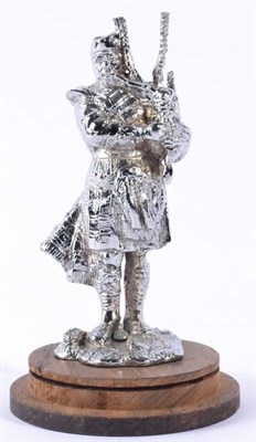 Lot 1035 - A Chrome on Brass Car Mascot, modelled as a Scottish Piper play bagpipes, standing on a rocky base