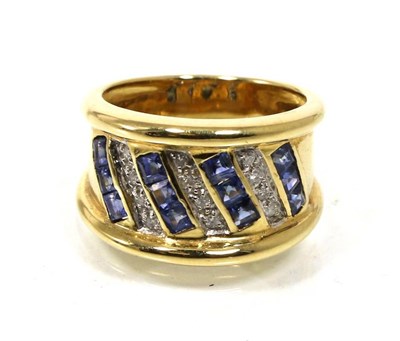 Lot 69 - A sapphire and diamond ring, four rows of channel set calibré cut sapphires, spaced by rows of...