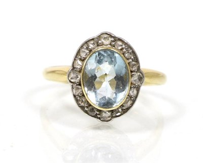 Lot 85 - An early twentieth century aquamarine and diamond cluster ring, an oval cut aquamarine in a...
