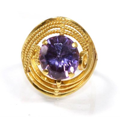 Lot 153 - An amethyst ring, an oval mixed cut amethyst within a plain bar and beaded frame, finger size...