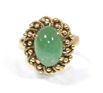 Lot 194 - A cabochon jade ring in a beaded border, finger size J, stamped '14K', 6.4g