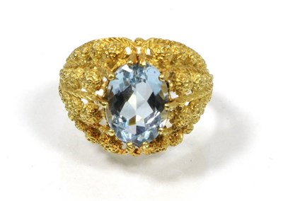 Lot 195 - An aquamarine ring, an oval cut aquamarine in a claw setting, within a broad tapering...