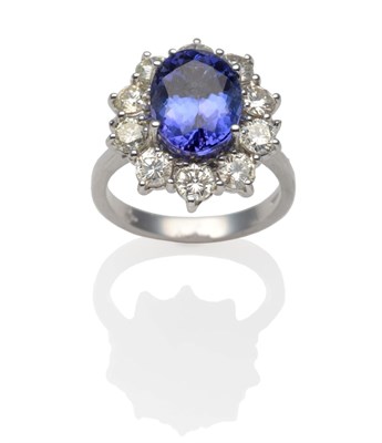Lot 191 - An 18 Carat White Gold Tanzanite and Diamond Cluster Ring, an oval cut tanzanite within a border of