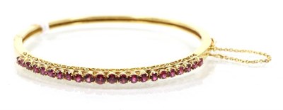 Lot 276 - A ruby bangle, the front with graduated round cut rubies, to a plain hinged back, measures 4.8cm by