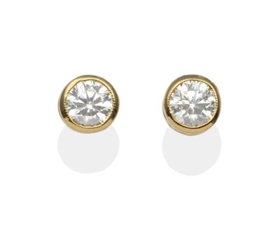 Lot 222 - A Pair of Diamond Solitaire Earrings, a round brilliant cut diamond in a yellow milgrain...