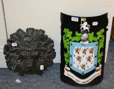 Lot 1225 - A cast iron and painted bow door with coat of arms and a cast metal green man wall mask (2)