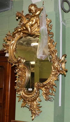 Lot 1260 - An elaborate rococo style gilt wall mirror with putto surmount (a.f.)