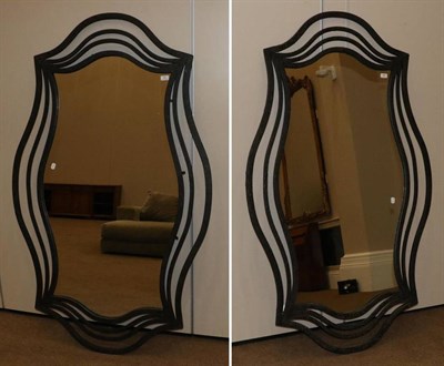 Lot 450 - A Pair of Black Metal Wrought Iron Effect Mirrors, modern, of serpentine shaped form, with...