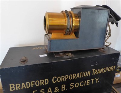 Lot 1276 - Magic Lantern Stamped 'Made In London' with 7'' brass lens, with electric lamp in fitted wooden...