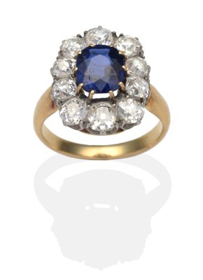 Lot 382 - A Sapphire and Diamond Cluster Ring, an oval cut sapphire in a yellow claw setting within an...