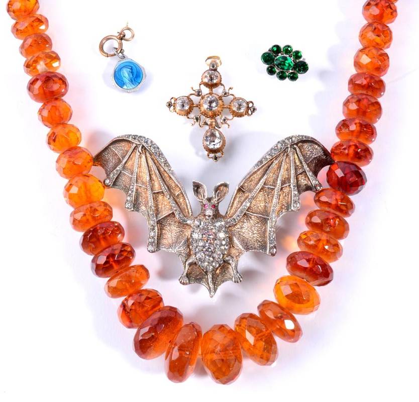 Lot 103 - An antique paste set cross pendant, a green paste set cluster brooch, a faceted amber bead...