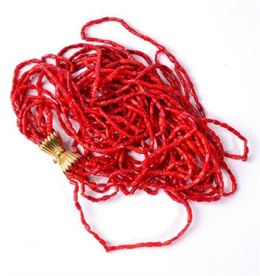 Lot 290 - A red coral necklace, multi-stands of coral branch beads knotted to a large fluted bow clasp,...