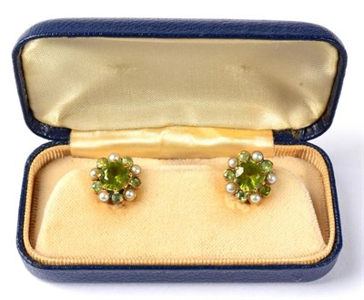 Lot 294 - A pair of peridot and seed pearl earrings, a round cut peridot within a border of alternating...