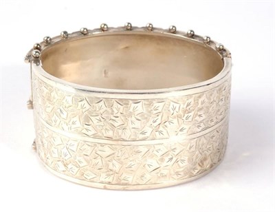 Lot 302 - A Victorian silver cuff bangle, with chased leaf detail and a beaded edge, measures 5cm by 6cm...